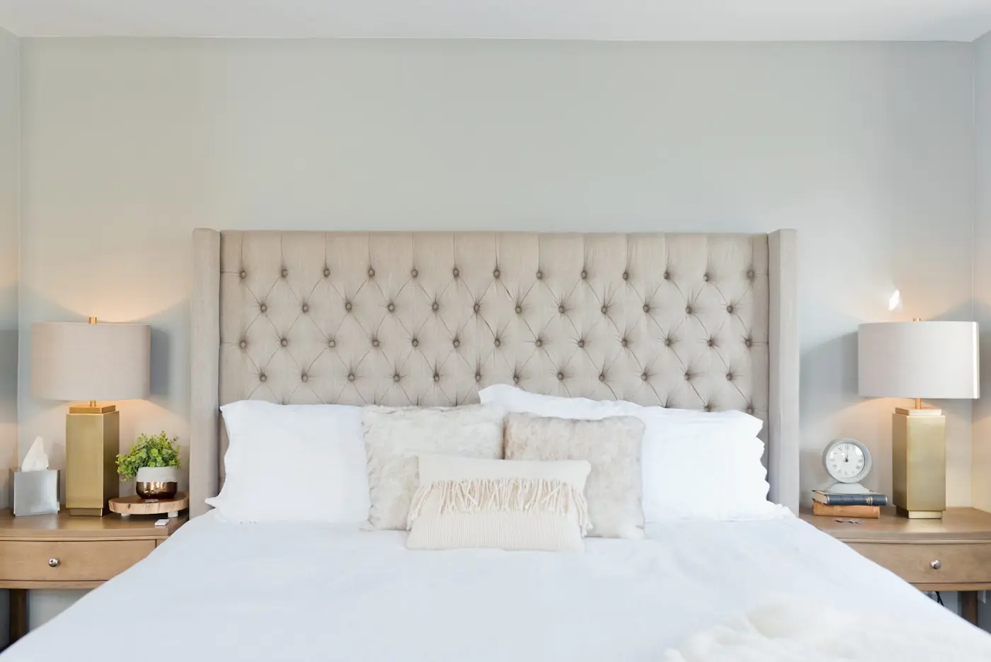 Detalle de la cama king con cabecera capitoné y lámparas cálidas